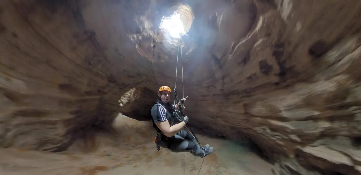 A 360 frame from inside Majlis al-Jinn in Oman, looking up at a climber abseiling towards the light