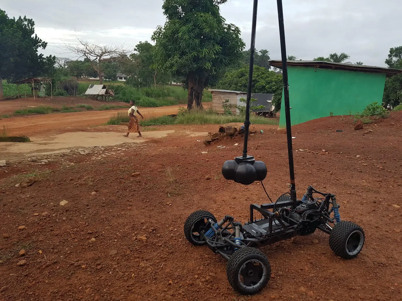 A 360 camera mounted on a remote-controlled rover on a red dirt track in Sierra Leone