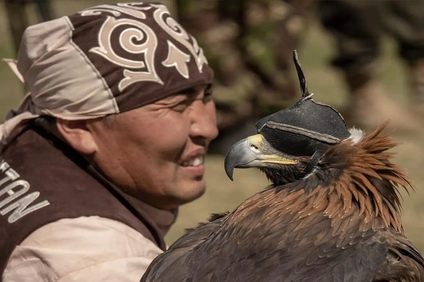 An eagle hunter at the World Nomad Games in Kyrgyzstan, face to face with his hooded eagle